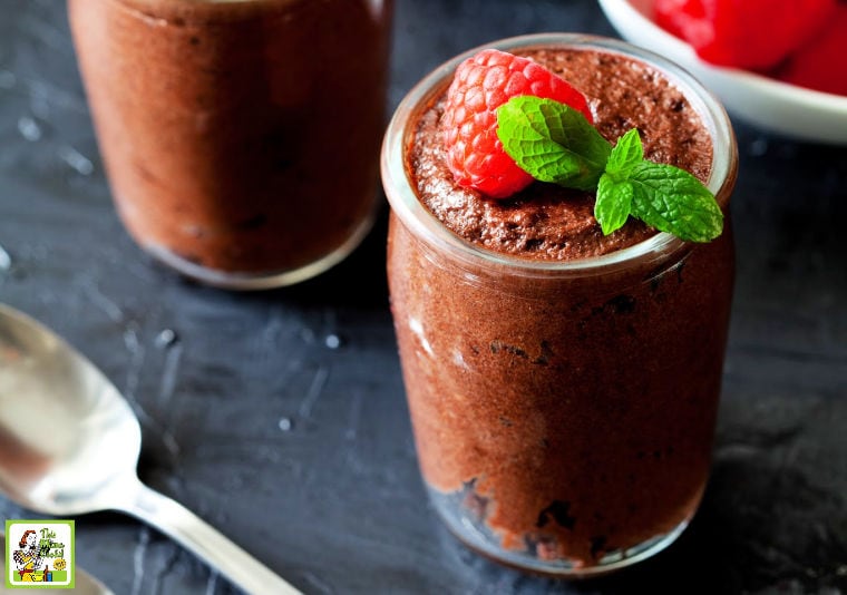 Glasses of chocolate mousse with raspberry and a mint leaf and a spoon.