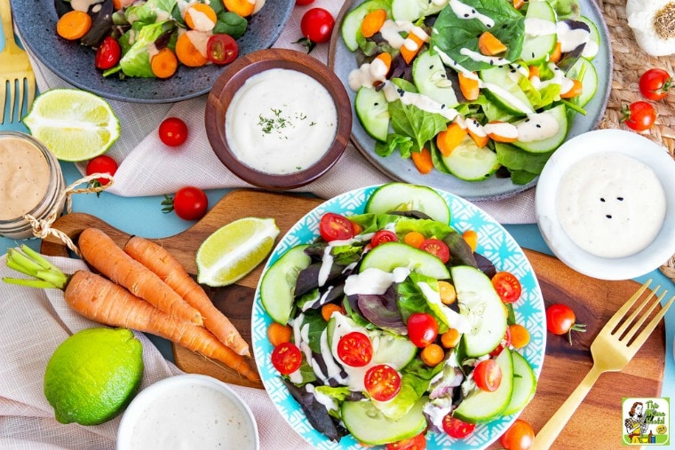 Several plates of salads, vegetables, and bowls of vegan salad dressings.