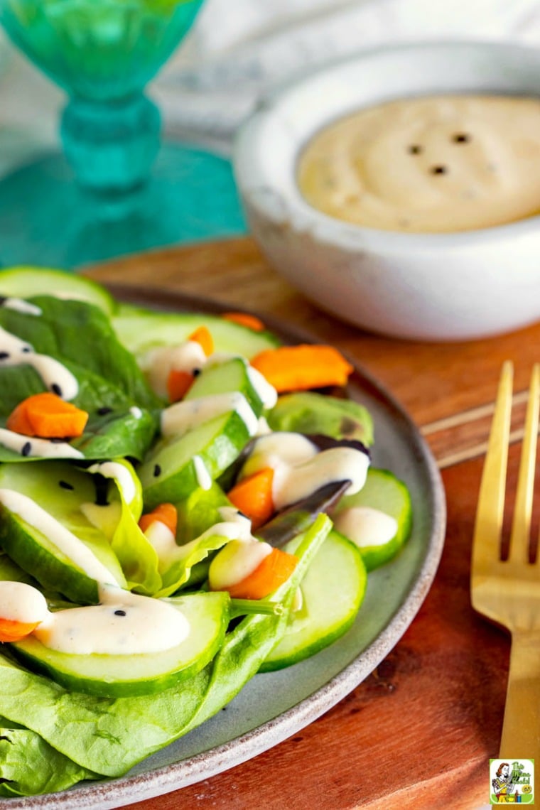 A plate of cucumber, lettuce and carrots dressed with a vegan salad dressing.