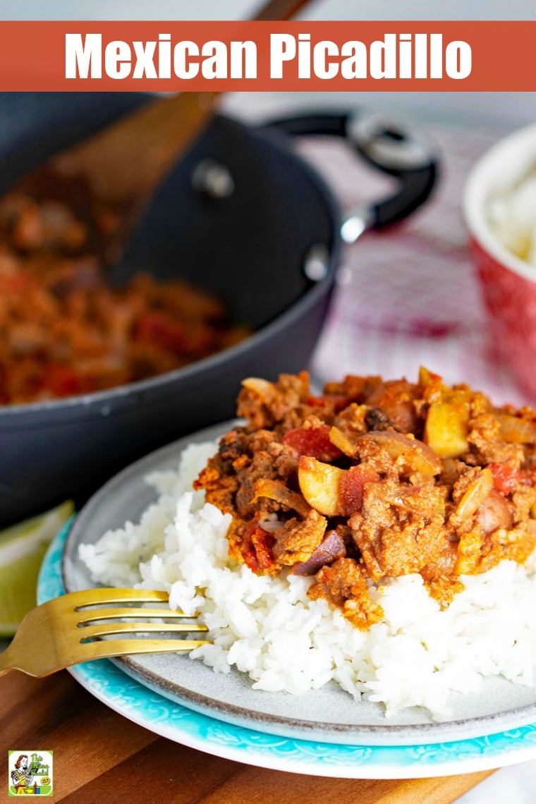 Plate of rice and Mexican Picadillo with fork and saute pan and wooden spoon and pink bowl in the background.