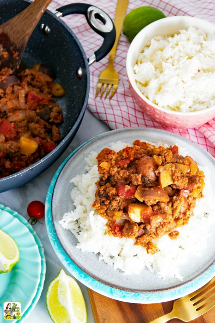 Mexican Picadillo served on rice, with bowl of rice, and picadillo in frying pan with wooden spoon.