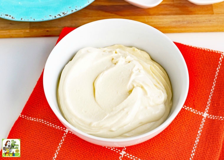 A white bowl of vegan sour cream on an orange napkin.