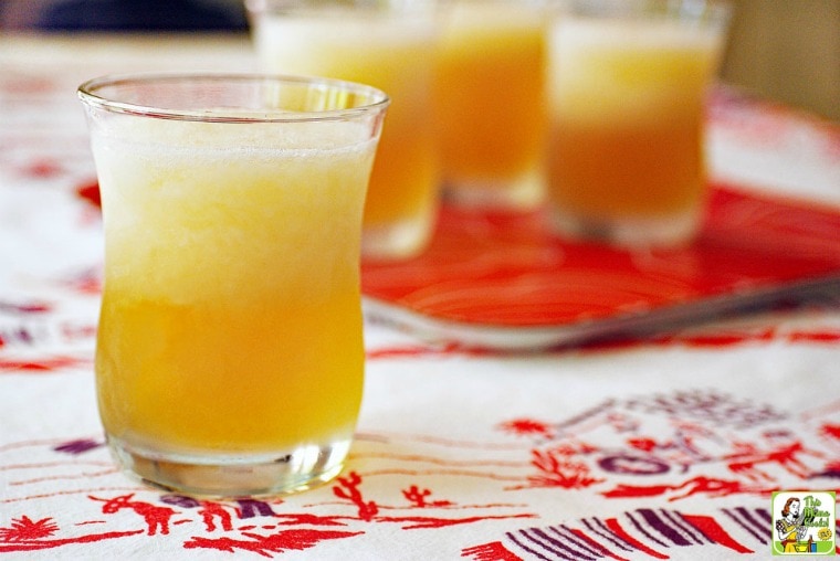 Glasses of Peach & Cherry Beer Margarita on a festive tablecloth.