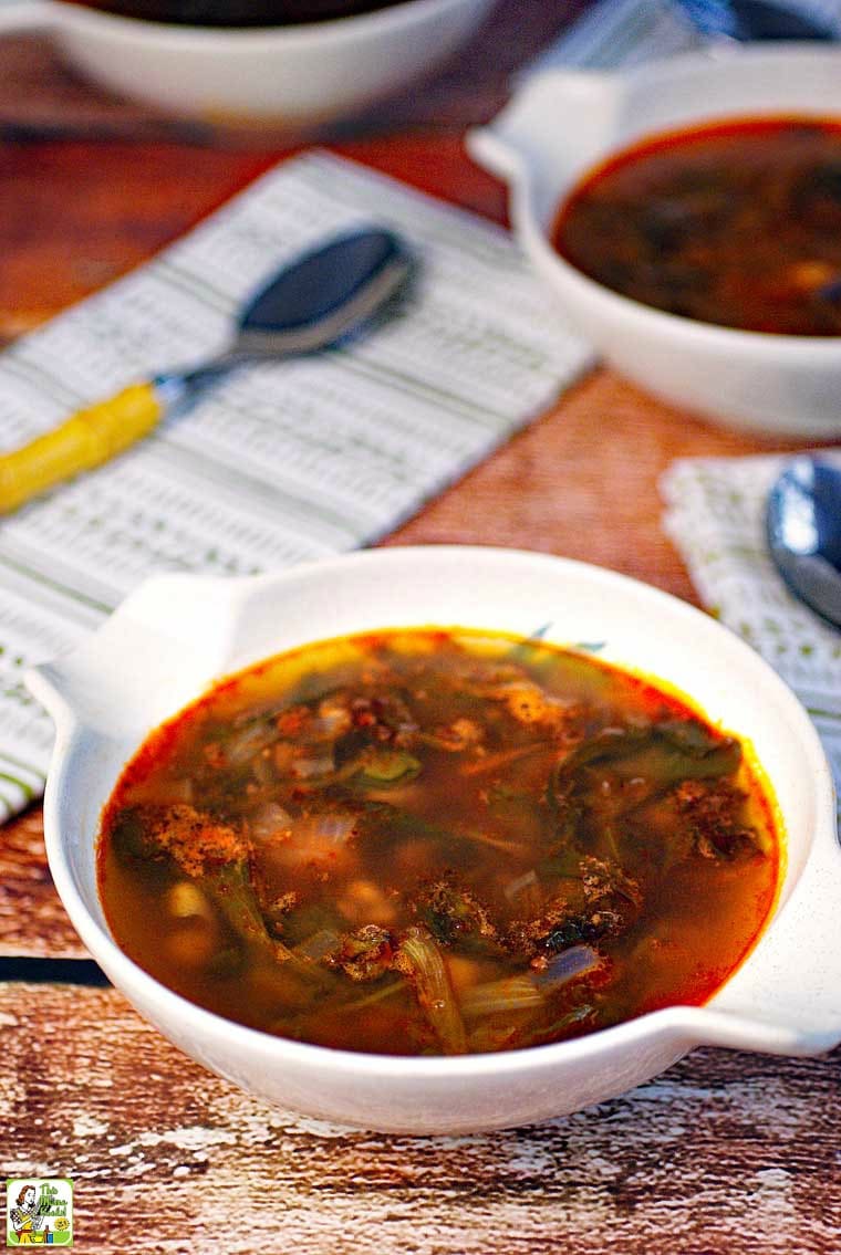 A bowl of Kale Soup with spoons and napkins