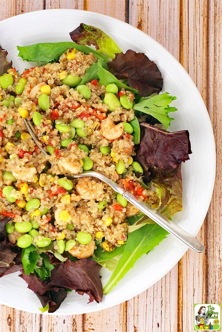 Closeup of quinoa, edamame, and shrimp salad with fork on a wooden tabletop.