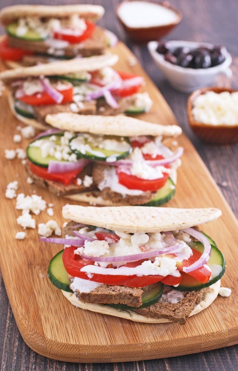 Closeup of homemade gyros on a wooden cutting board with feta cheese.