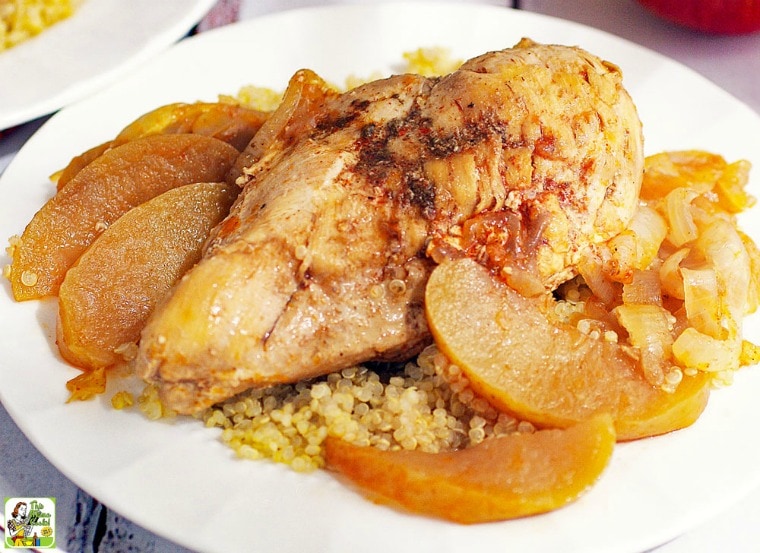 Chicken Normandy with onions and apples on a bed of quinoa on a white plate.