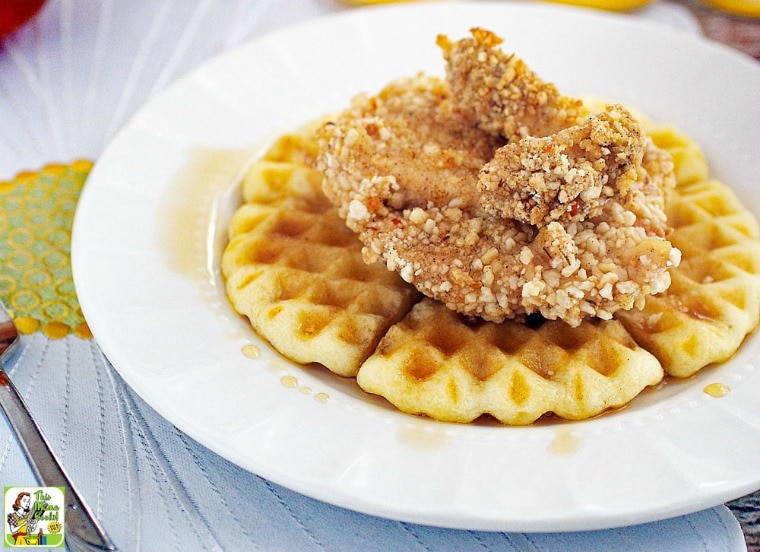 Baked chicken and waffles with maple syrup on a white plate.