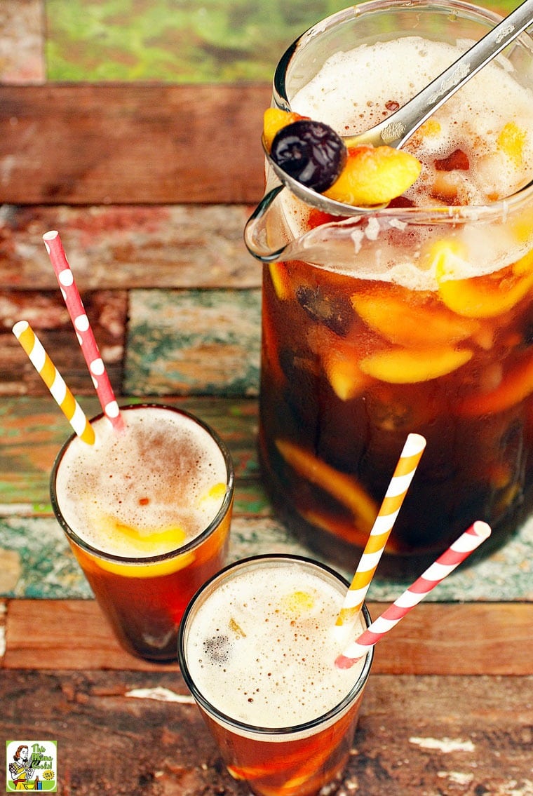 A pitcher and glasses with straws of iced tea with fruit. 