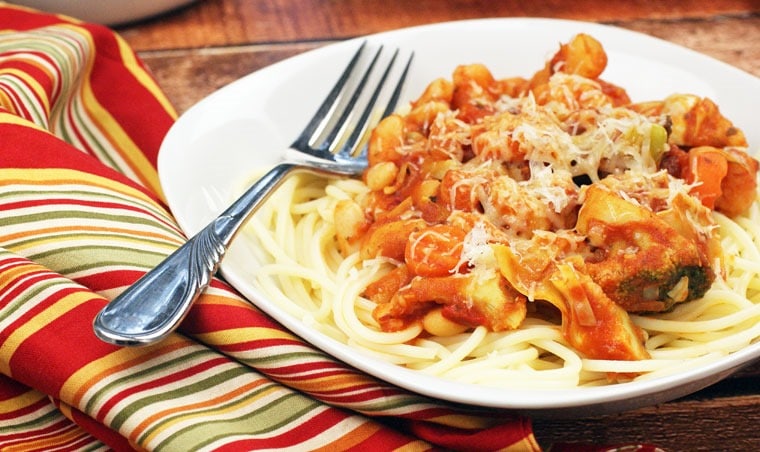 A plate of Pasta Recipe with Cannellini Beans & Italian Veggies with fork and napkin.