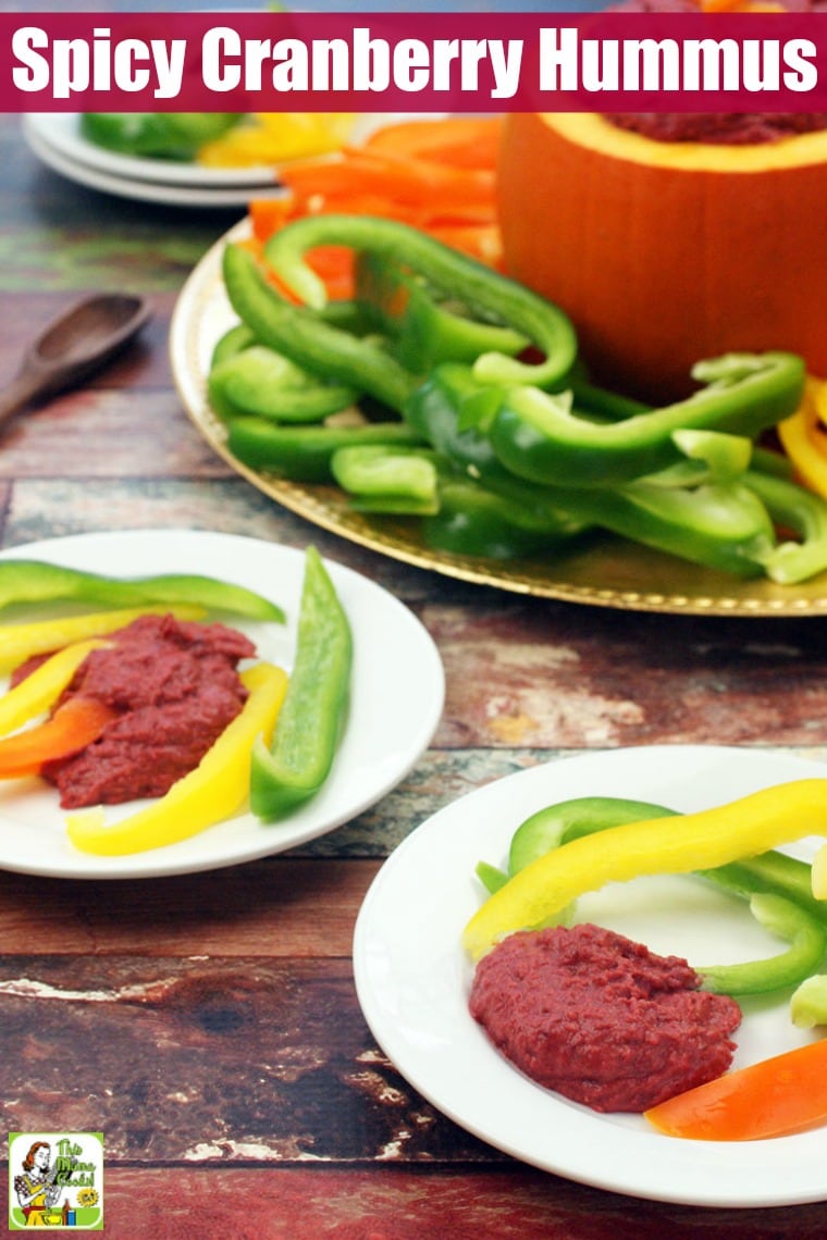 Plates of spicy hummus and hummus served in a pumpkin on a gold platter with veggie dippers.