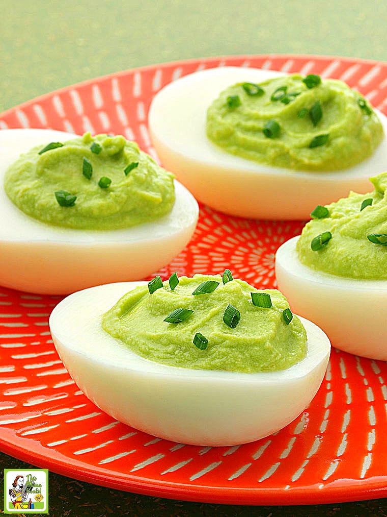 An orange plate filled with Avocado Deviled Eggs with chives.