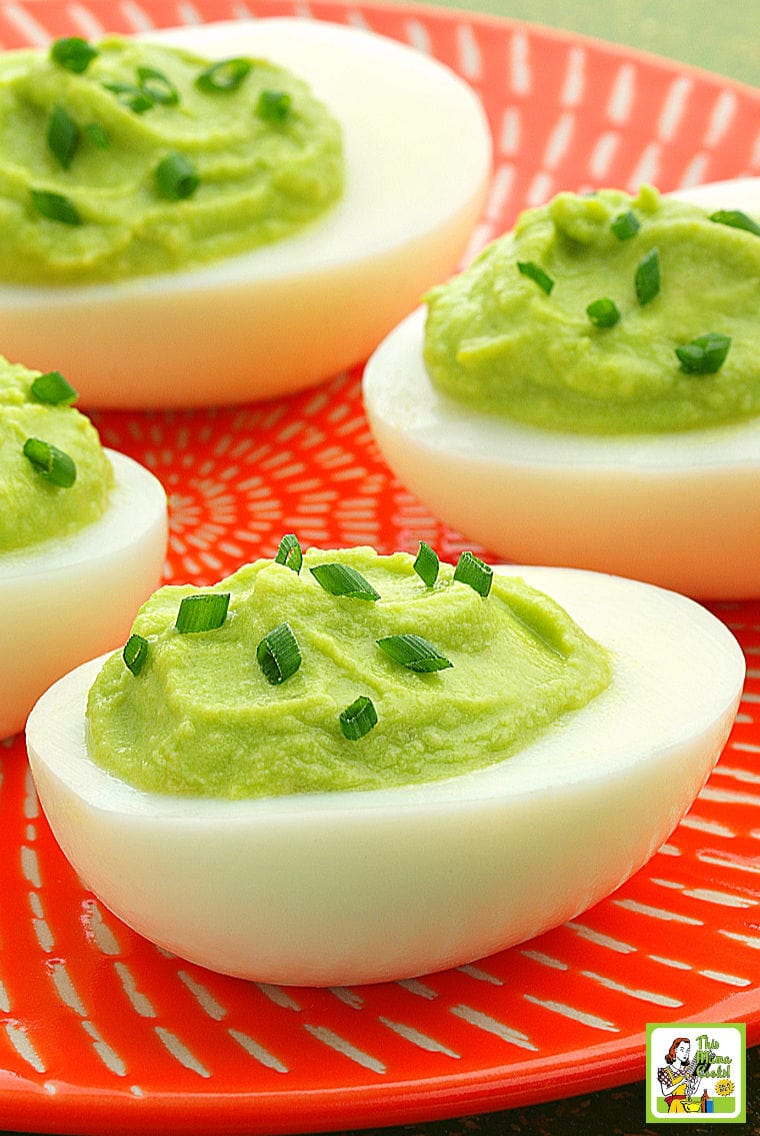 An orange plate filled with Avocado Deviled Eggs.