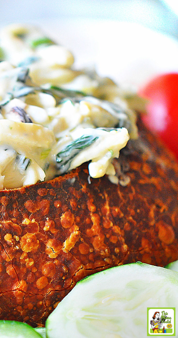 Crab and spinach dip served in a bread bowl with vegetables.