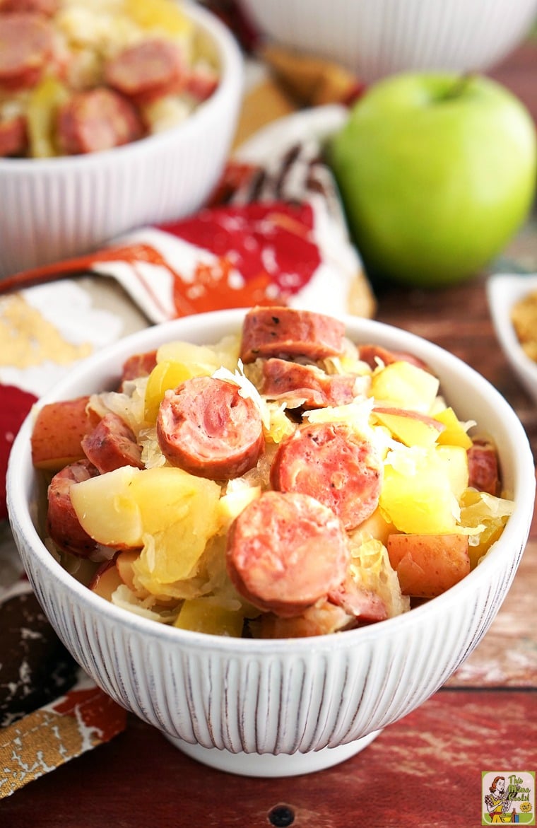Slow Cooker Sauerkraut and Sausage with Apples and Potatoes in a white bowl.