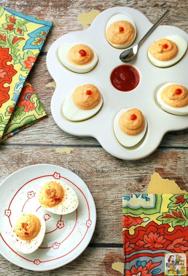 Two white plates of deviled eggs with napkins and a serving spoon.