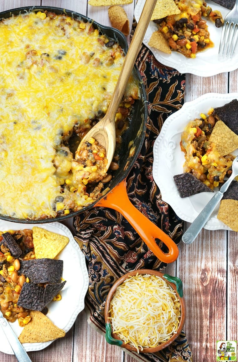 Skillet of Easy Nachos, chips, and cheese on plates.