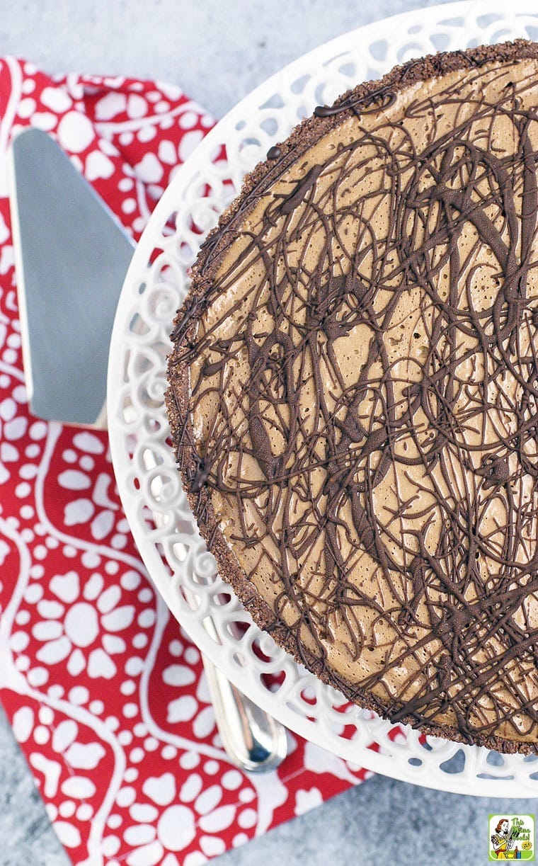 Closeup of a Chocolate Pie on a white cake stand with a red napkin and knife.