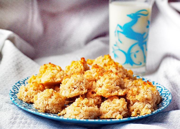 A plate of Coconut Macaroons cookies with a glass of milk.