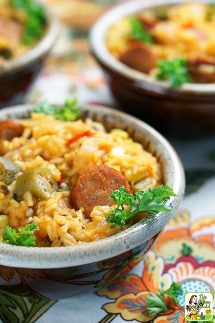 Closeup of bowls of Andouille sausage jambalaya with sprigs of parsley on a colorful floral napkin.
