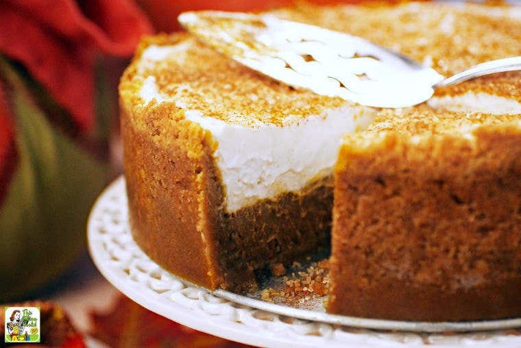 Gluten free dairy free pumpkin pie with a slice missing with a serving knife on a white cake stand.