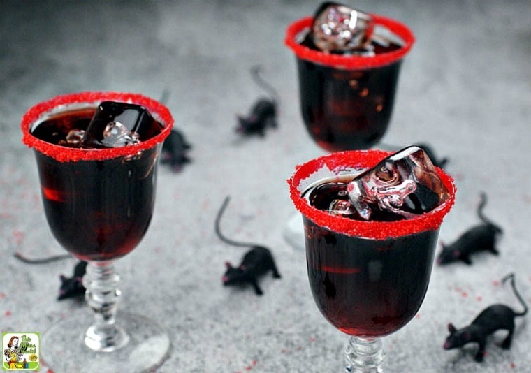 Three glasses of black cocktails rimmed in red sugar.