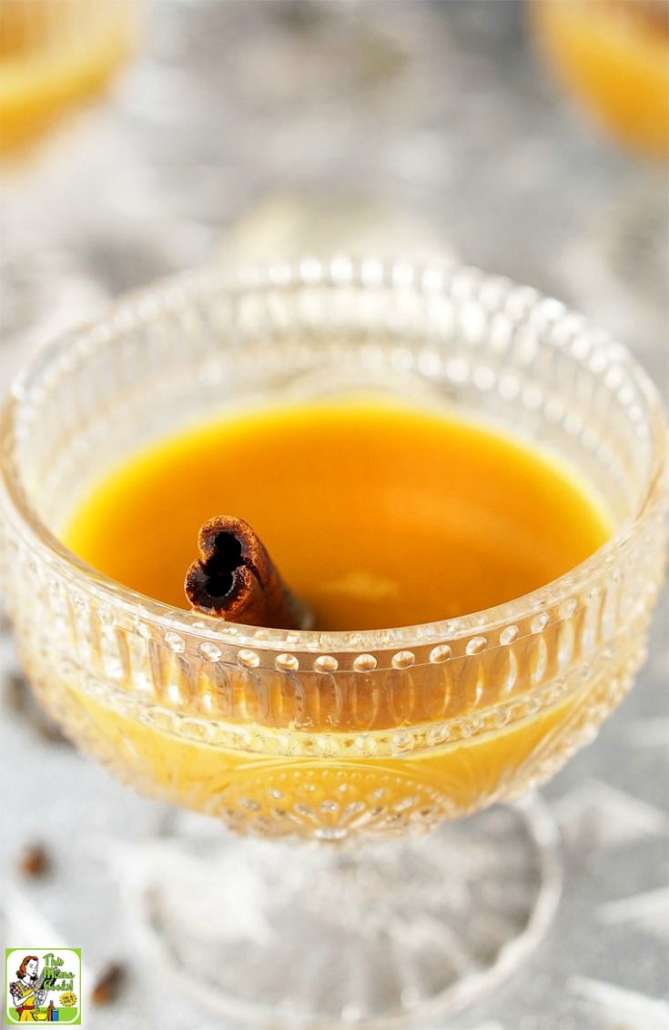 Punch glass filled with orange tea cocktail and cinnamon stick.
