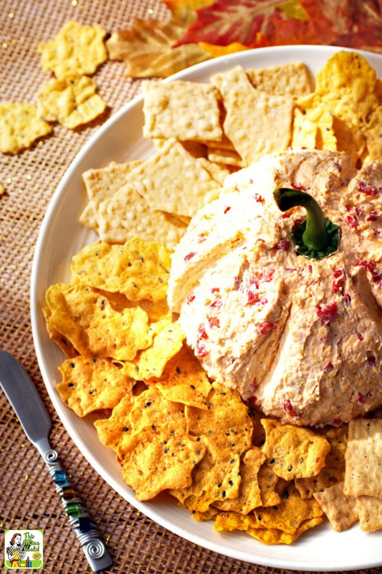 Pimento Cheese Pumpkin with crackers on a white plate with a silver knife.