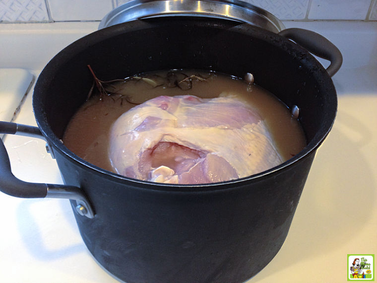 Placing the turkey breast in the pot of smoked turkey breast brine.