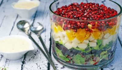 A layered Mexican Christmas Salad in a glass trifle bowl