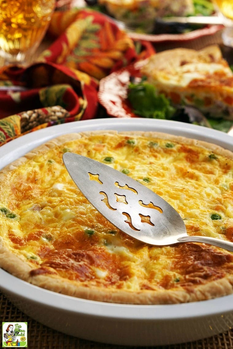 Closeup of a pie plate of quiche with a serving spoon.