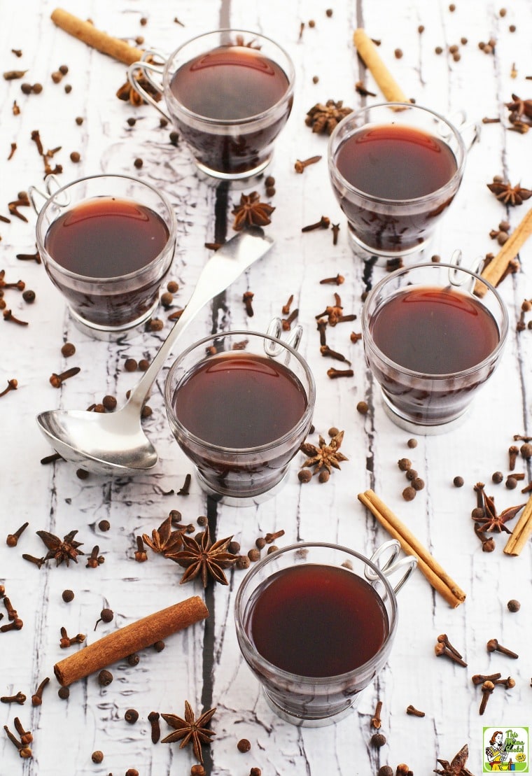 Hot mulled wine in glasses with spices and ladle.