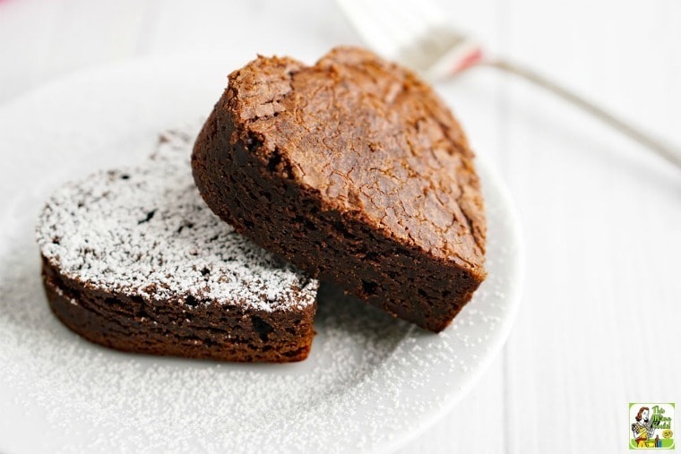 Heart shaped brownies dusted with powdered sugar on a white plate with fork.