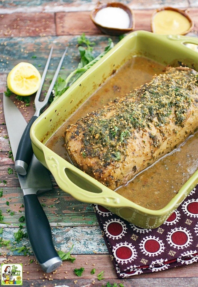 Herb & Lemon Pork Loin Marinade Roast in a roasting pan with knives and a napkin.