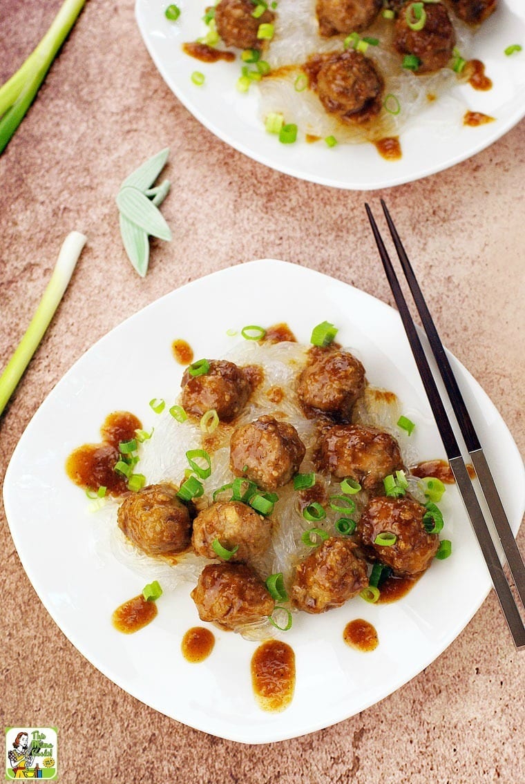 Overhead view of Gluten Free Asian Meatballs with Hoisin Sauce on a white plate with chopped green onions and chopsticks.
