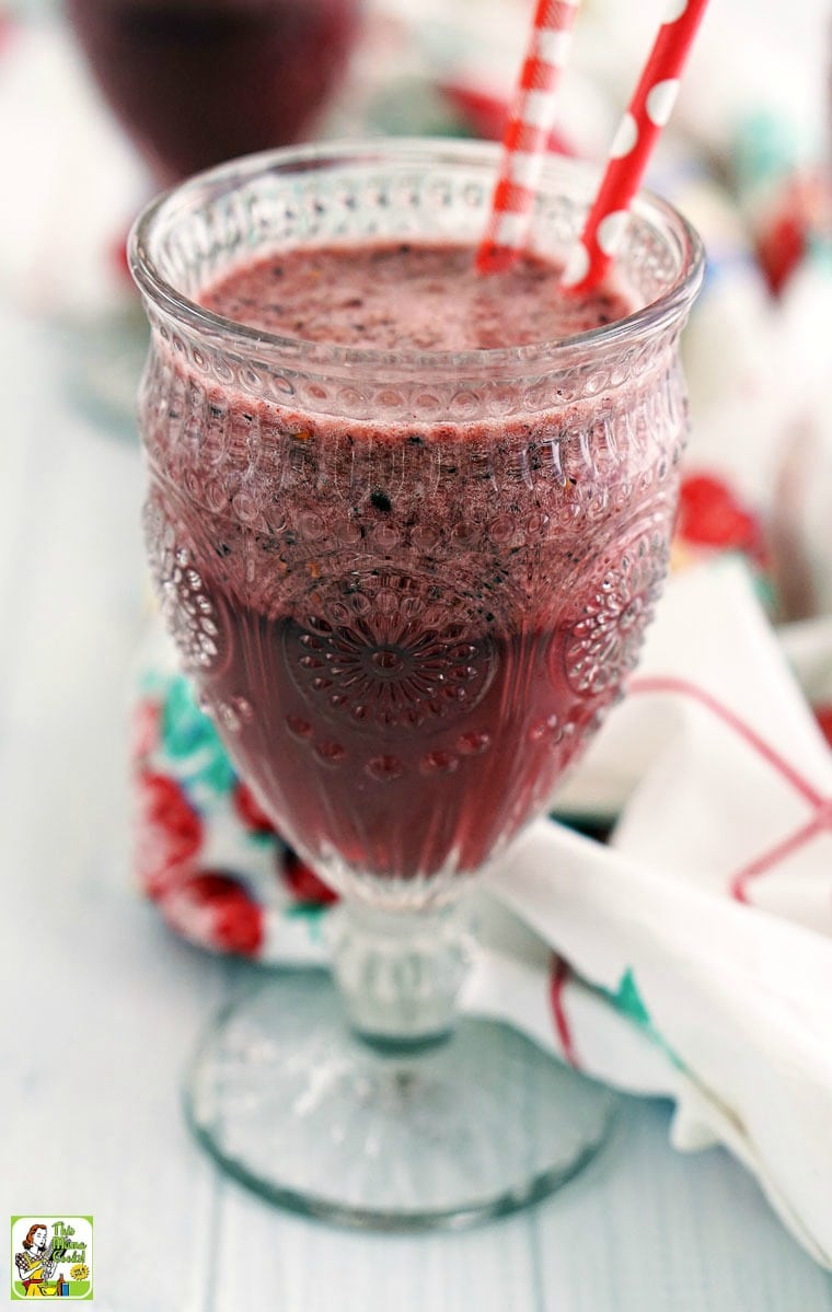 Closeup of an antique glass of filled with a berry smoothie with red straws.
