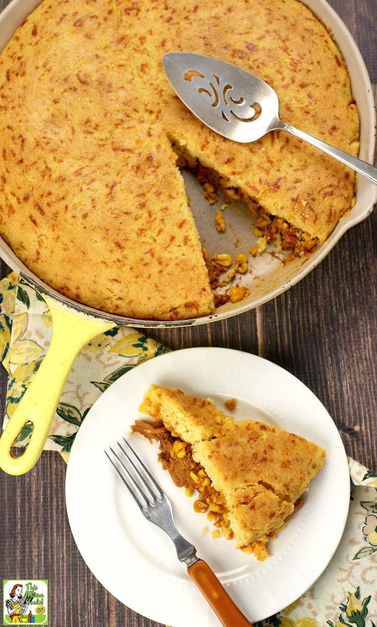 A white plate of Pulled Pork Skillet with Cornbread, fork, napkin, and skillet.