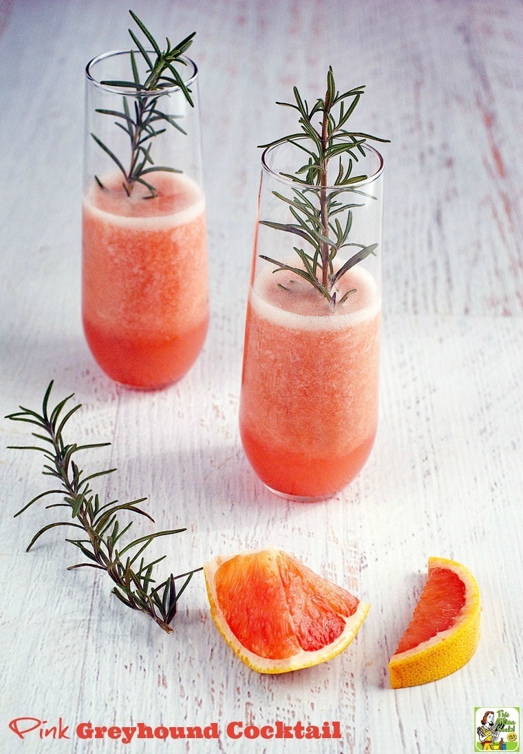 Glasses of Pink Greyhound Cocktails with sprigs of rosemary and slices of pink grapefruit.