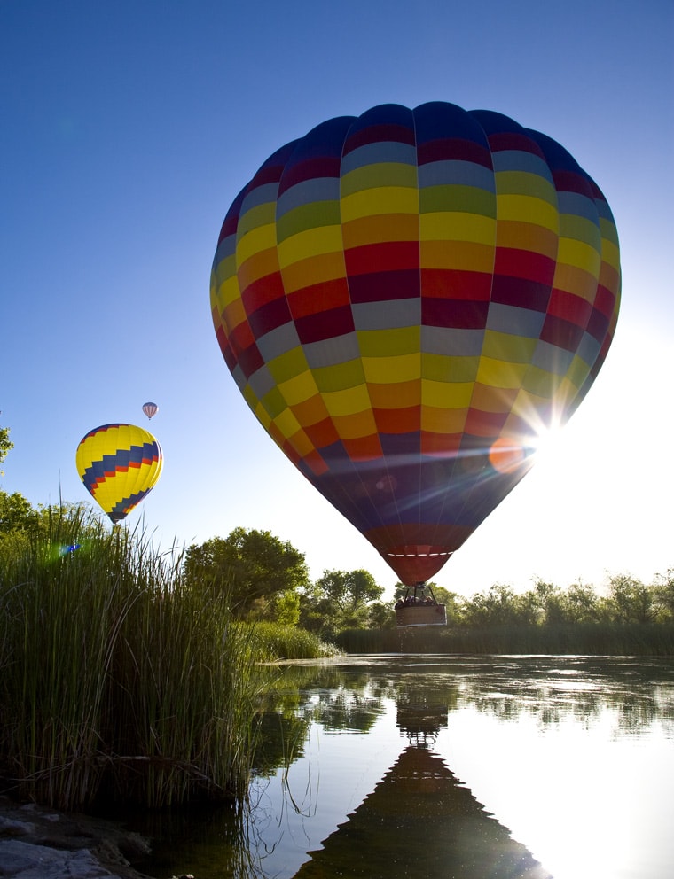 Backlit hot air balloons on the water in Temecula, California.