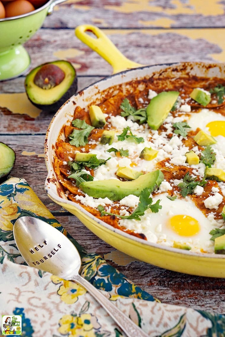 A skillet of breakfast chilaquiles with eggs, salsa, and avocados. 