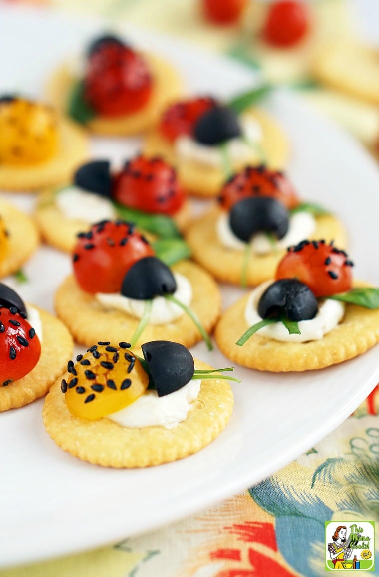 Closeup of Caprese Ladybugs tomato, cheese, basil and olive appetizer on a cracker.