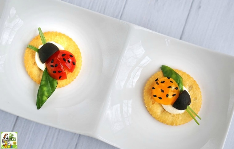 Tomato and cheese ladybugs snack cracker appetizers on a white dish.