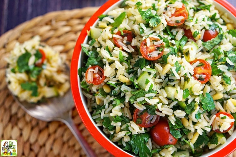 Gluten Free Tabbouleh with parsley and tomatoes in a orange bowl with serving spoon.