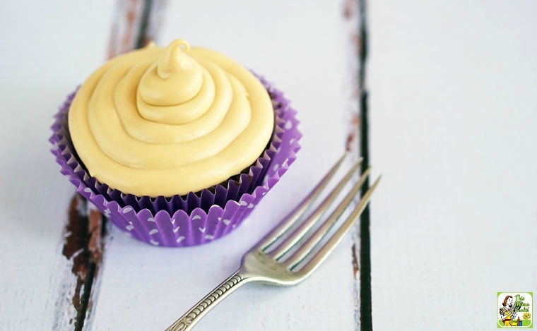 A closeup of a Chocolate Cupcake with Dulce de Leche Frosting with a colorful cupcake liner and an antique silver fork.