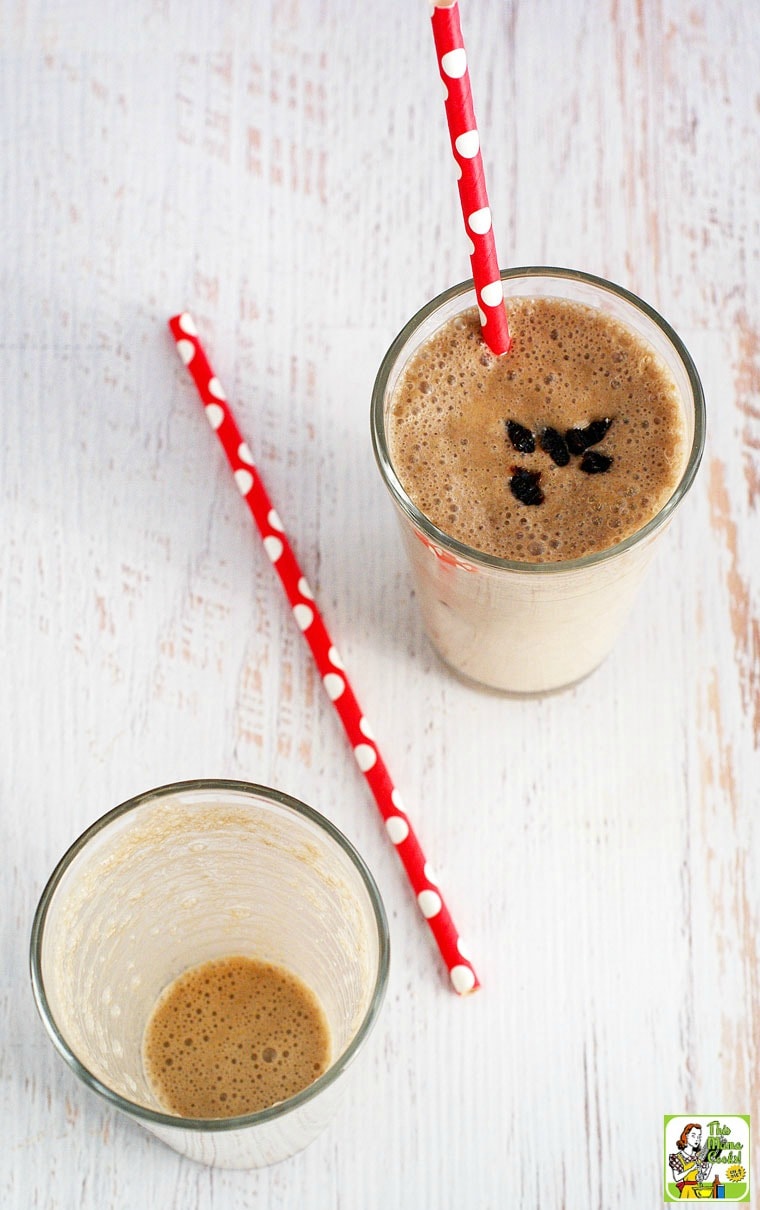 Two glasses of banana smoothie with red straws, one full, one empty.