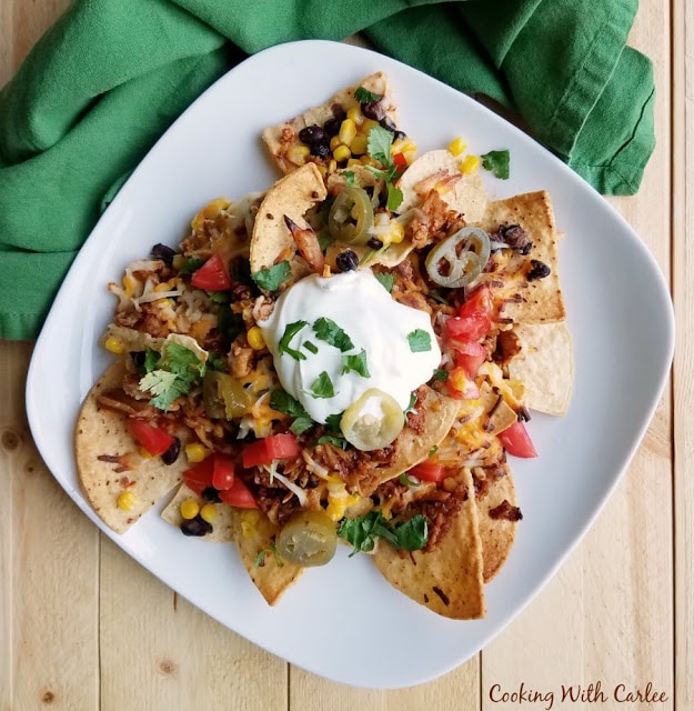 Plate of Loaded Veggie Pulled Pork Nachos with green napkin.