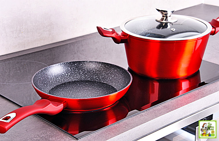 Red frying pan and sauce pot with glass lid on induction cooktop stove.