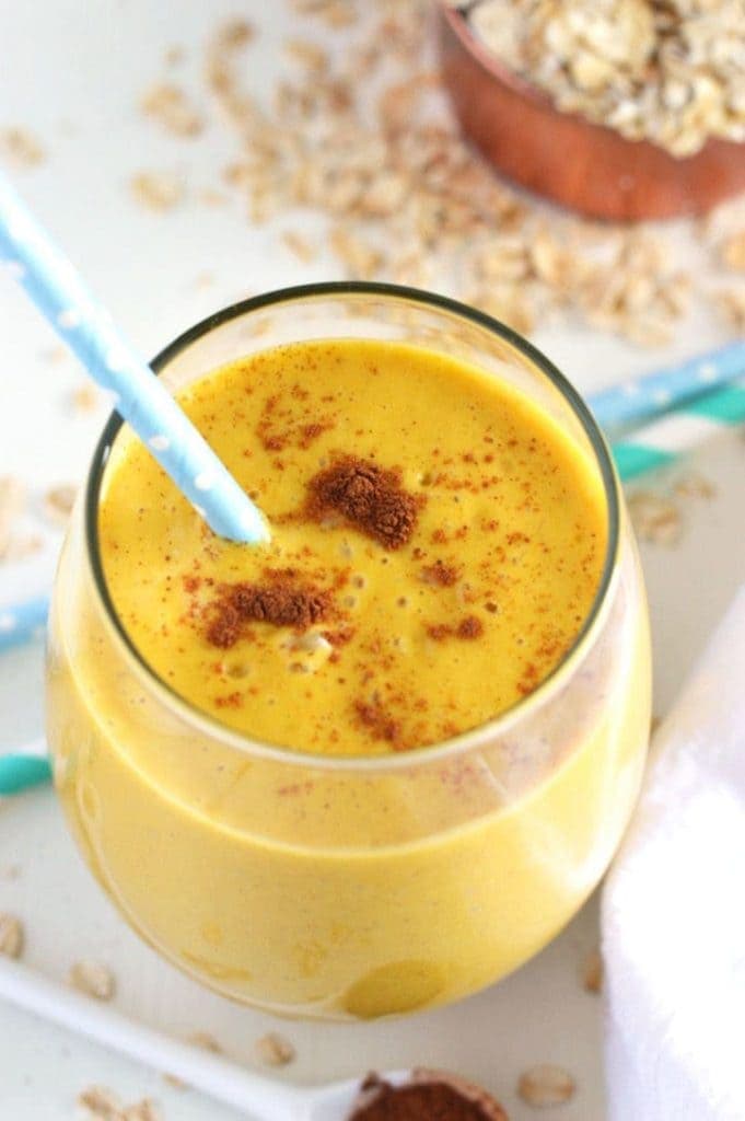 A glass of Pumpkin Pie Oatmeal Smoothie served with a straw.