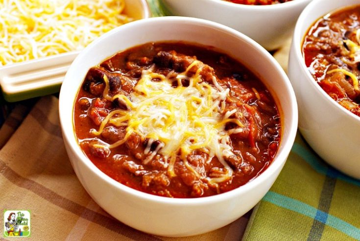 Bowl of turkey pumpkin chili with beans and shredded cheddar cheese