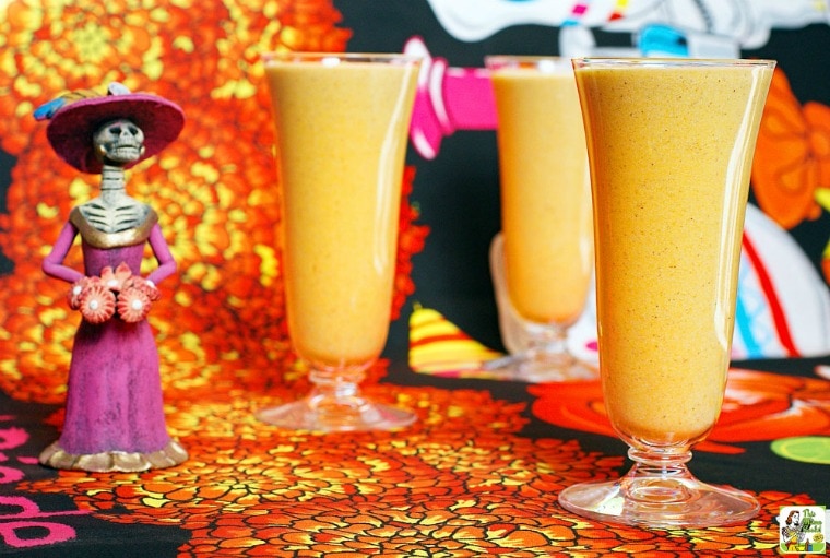 Glasses of Pumpkin Pie Smoothie with a Dia de los Muertos figurine.